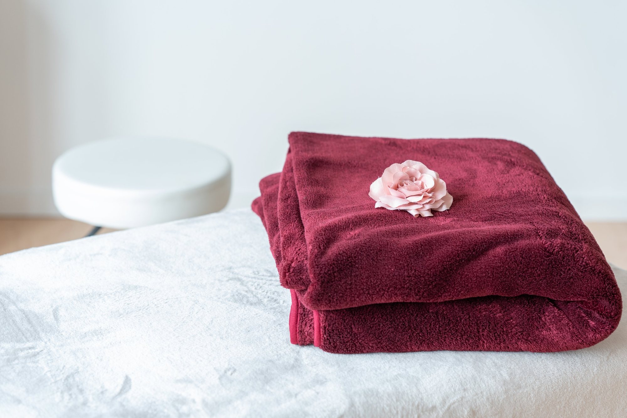 Gefaltetes bordeauxfarbenes Handtuch mit einer rosa Blüte