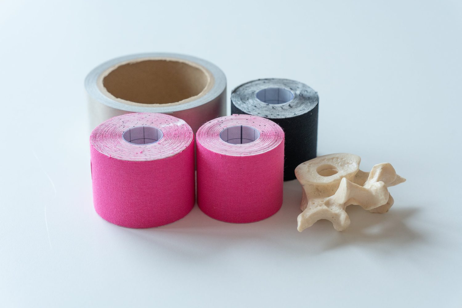 Rollen Kinesiotape und ein Wirbelmodell auf weißem Tisch